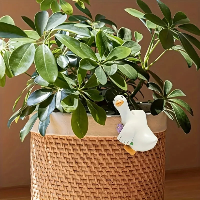 Figurine canard en résine suspendue au bord d'un pot de fleurs