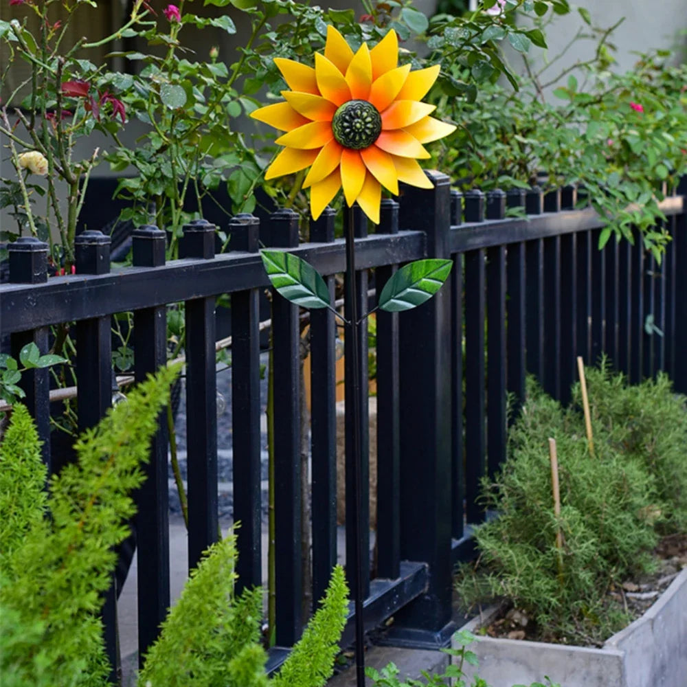 Moulin à vent de jardin en métal avec motif tournesol planté dans une pelouse